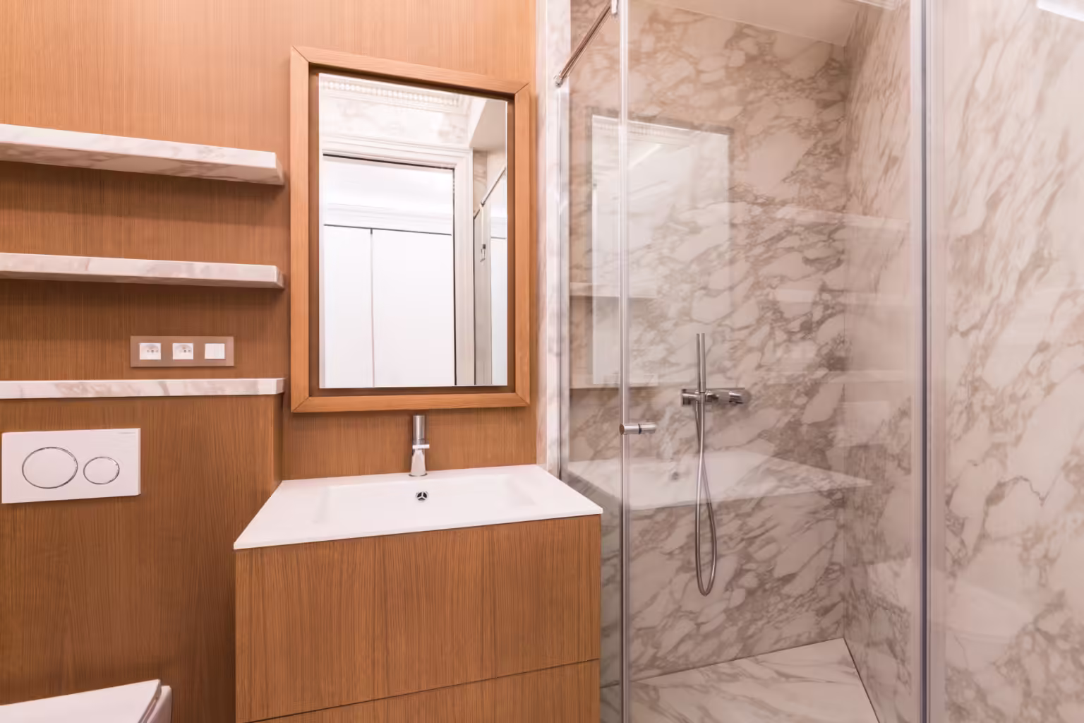 Salle de bain en marbre gris, niches en bois et douche vitrée